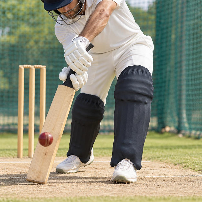 Batter playing a defensive shot with plain black stretch skin covers fitted over batting leg guards
