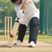 Batter playing a defensive shot with plain black stretch skin covers fitted over batting leg guards