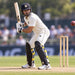 Batter wearing CA Gold 20K black cricket batting leg guards in an outdoor match