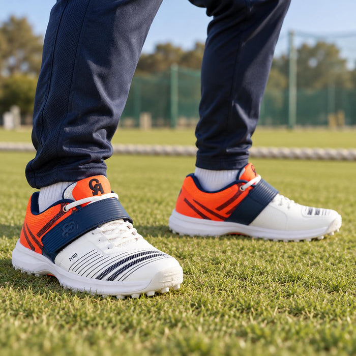 Cricketer wearing White Navy Orange CA M8 rubber stud shoes in a fielding stance