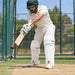 CA Plus 15000 white batting leg guards with gold CA logo worn by cricketer playing a defensive shot in cricket nets