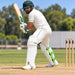 Cricketer wearing CA Plus 15000 white batting pads with gold branding and green rear straps in batting stance