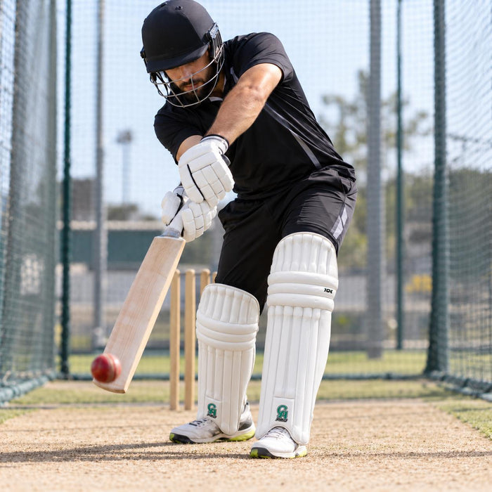 CA Pro 10K white batting leg guards worn by a cricketer playing a defensive shot in practice nets