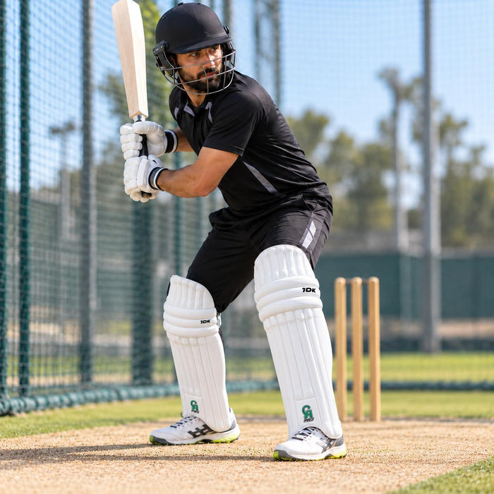Cricketer wearing CA Pro 10K batting pads with white front, green CA PRO logo and 10K branding in ready batting stance