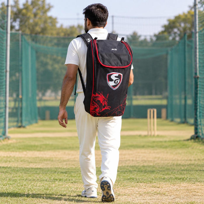 Cricketer carrying the black and red SG Dragon Ace kit bag with both shoulder straps
