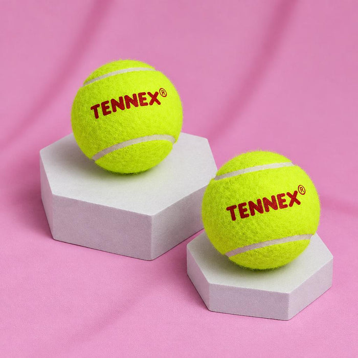 Two green Tennex balls on display blocks against pink fabric