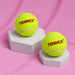 Two green Tennex balls on display blocks against pink fabric