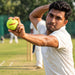 Cricket player holding a green Tennex cricket tennis ball