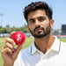 Cricket player holding a red SG synthetic cricket ball