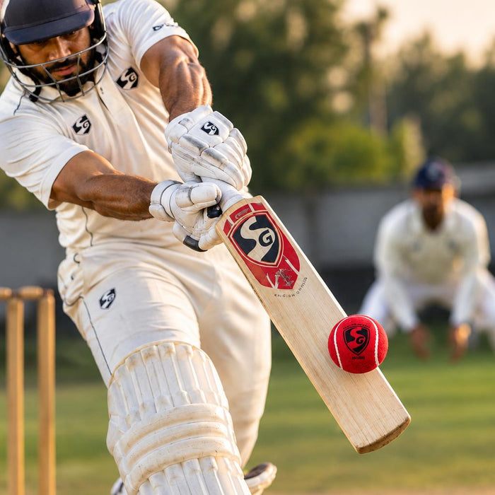 Cricket batsman playing a shot with a red SG tennis cricket ball
