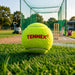 Green Tennex cricket tennis ball beside cricket practice nets