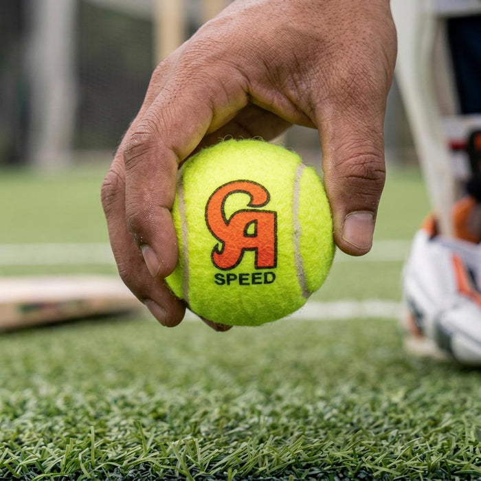 Hand holding a neon yellow CA Speed cricket ball