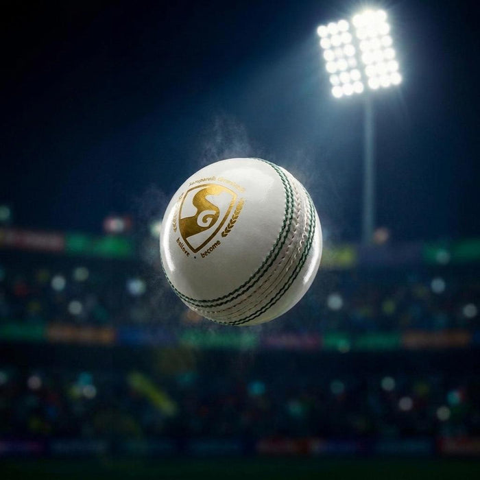 SG Club White Youth leather cricket ball against a floodlit stadium background