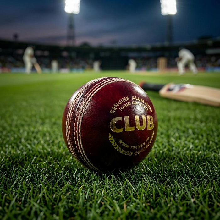Red SG Club Youth cricket ball on grass in a floodlit stadium