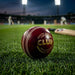 Red SG Club Youth cricket ball on grass in a floodlit stadium