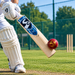 Red SG synthetic cricket ball contacting a bat during practice