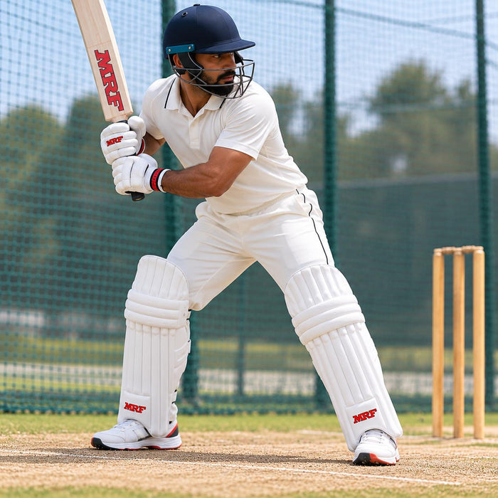 Cricketer wearing white MRF batting leg guards in a batting stance in practice nets