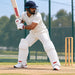 Cricketer wearing white MRF batting leg guards in a batting stance in practice nets