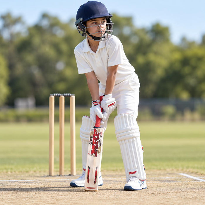 MRF Genius Master Class English Willow Cricket Bat - Junior Size 6 shown held in a batting guard with full cricket protective equipment