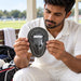 Adult cricketer inspecting the MRF Genius abdomen guard while preparing his cricket kit