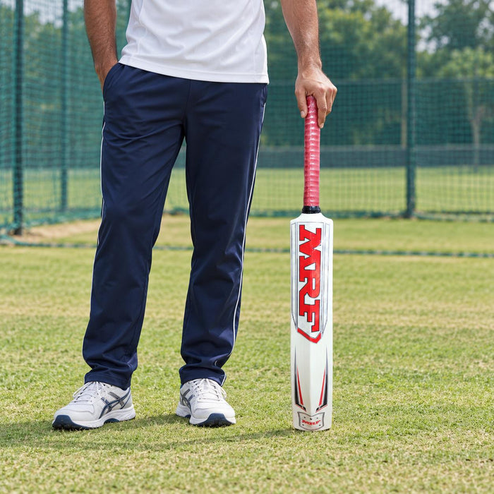 Adult holding the MRF Jumbo white plastic cricket bat with pink grip beside a practice net