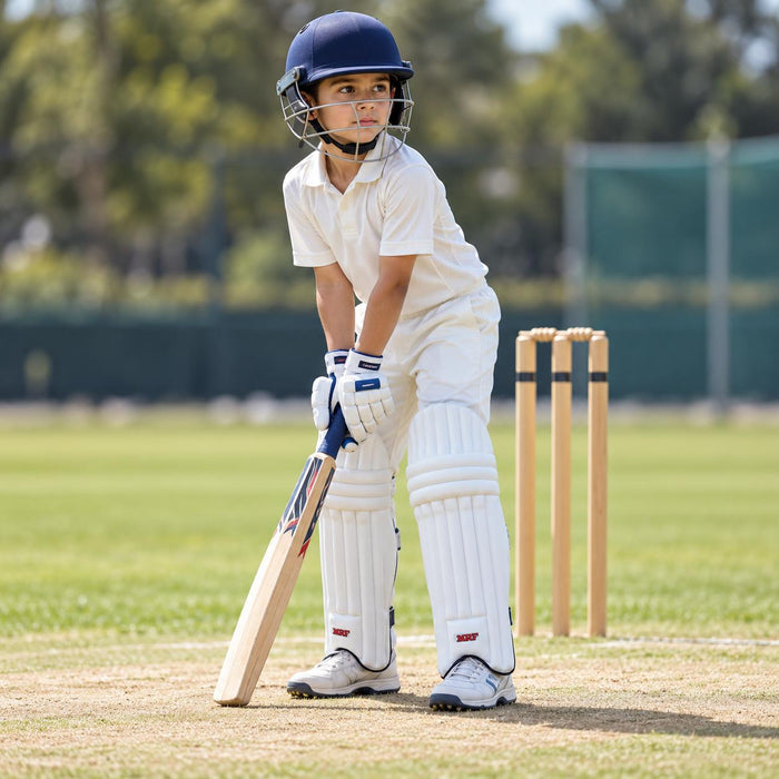 Small boy wearing white MRF Prodigy batting leg guards during junior cricket practice