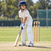 Small boy wearing white MRF Prodigy batting leg guards during junior cricket practice