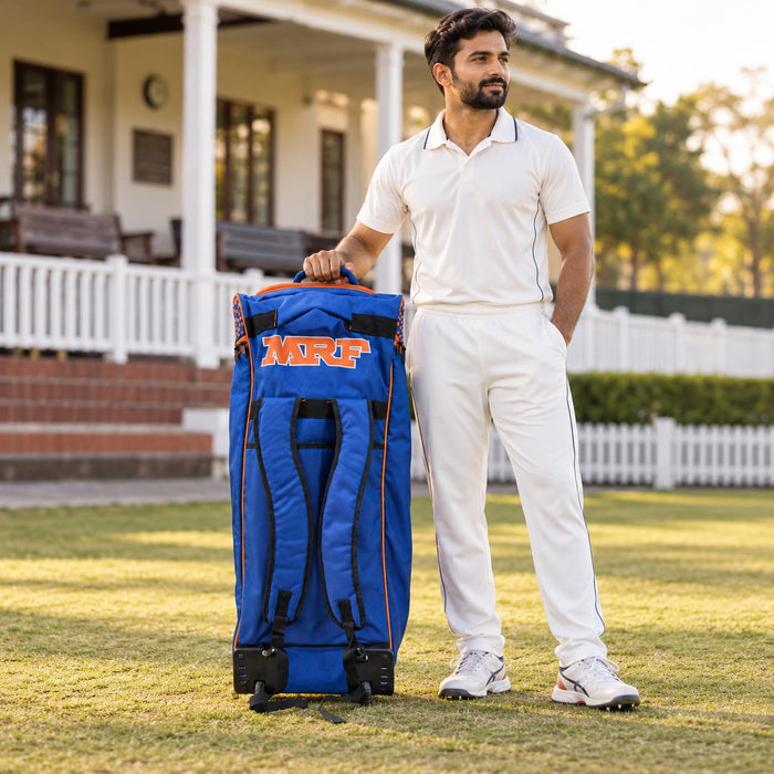 MRF VK 18 blue and orange senior kit bag beside a cricketer - rear straps and wheelbase