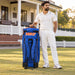 MRF VK 18 blue and orange senior kit bag beside a cricketer - rear straps and wheelbase