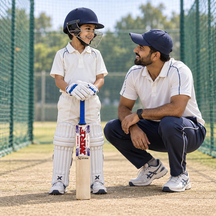 Junior cricketer holding the MRF Xstorm Size 1 bat correctly beside a coach