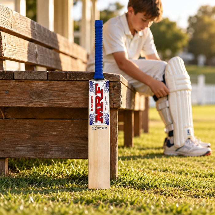MRF Xstorm junior Size 1 cricket bat beside a player preparing batting pads
