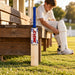 MRF Xstorm junior Size 1 cricket bat beside a player preparing batting pads