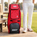 MRF Genius Emperor red and grey kit bag beside a cricketer at the pavilion
