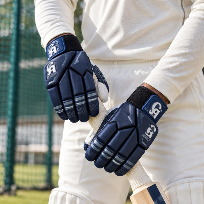 CA Pro 10000 navy batting gloves worn while gripping a cricket bat