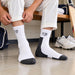 Cricketer wearing SG Club white and black socks while preparing on a changing-room bench