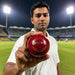 Adult cricketer holding a red SG Shield 20 leather cricket ball on a floodlit cricket ground
