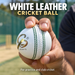 White leather cricket ball with green stitching held in a seam grip