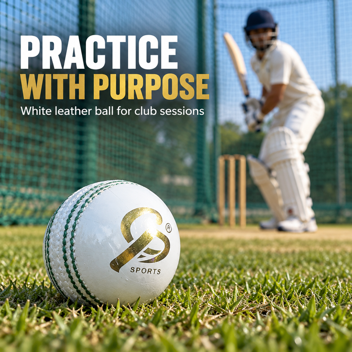 White leather cricket ball with gold logo on grass beside practice nets